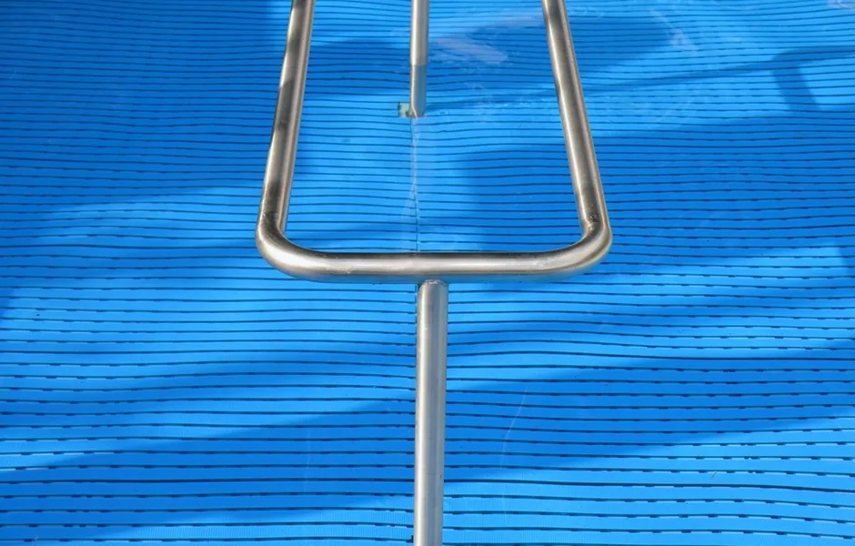 A pool ladder rail over rippling water