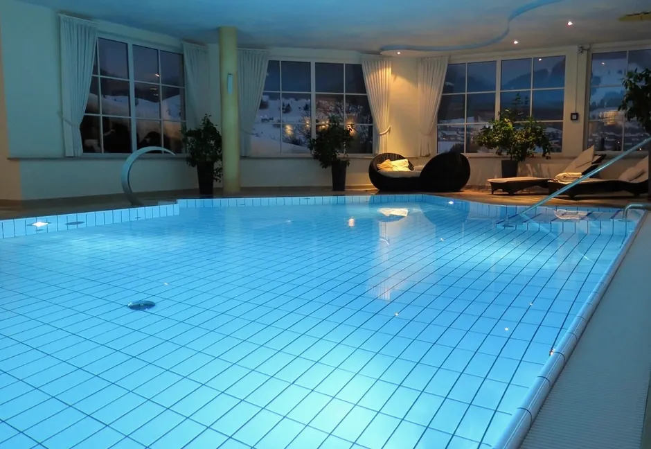 A sunny indoor pool with large windows