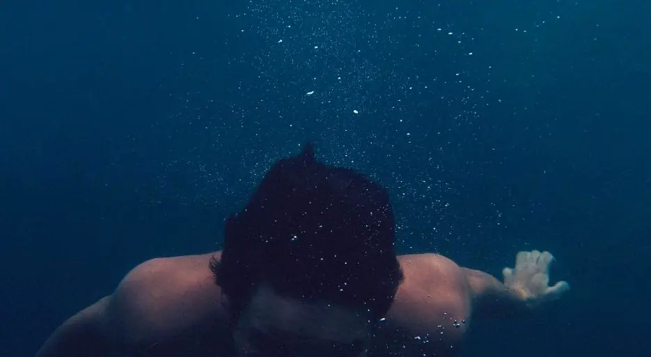 A swimmer pushing off under the surface