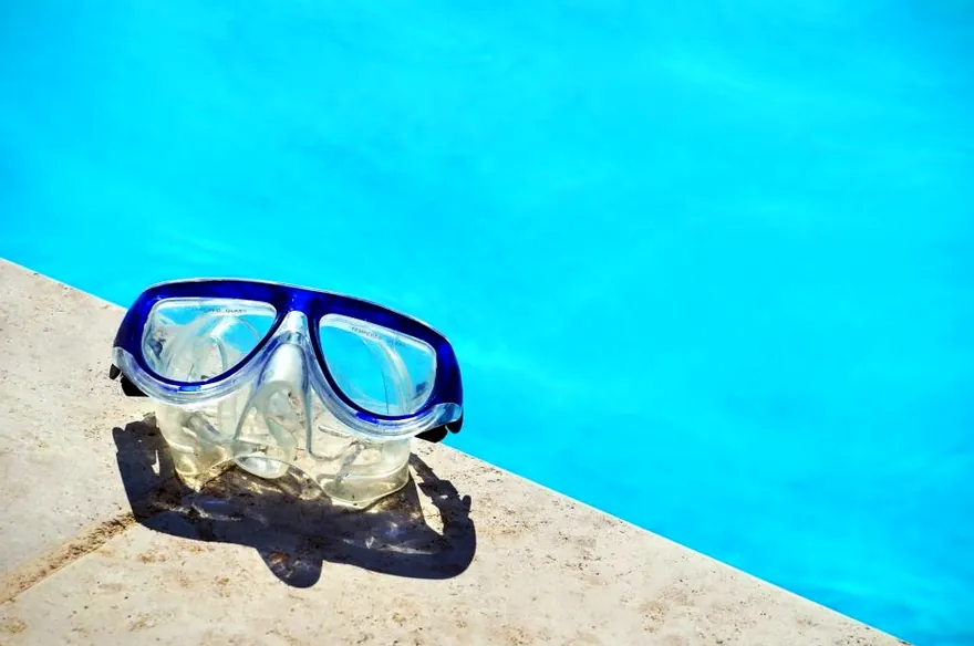 Swimming goggles on the edge of a pool